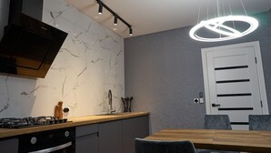 Une cuisine moderne avec un dosseret en marbre, une cuisinière encastrée et une table à manger en bois avec des chaises.