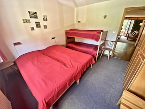 A dormitory room with bunk beds, a small desk, and a chair.