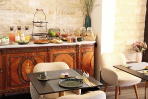 Un desayuno dispuesto con un mueble de madera, una mesa de comedor y un plato verde, junto a varios productos para el desayuno.