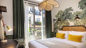 Ein Hotelzimmer mit Bett, Schreibtisch, Lampe und Blick auf einen Balkon.