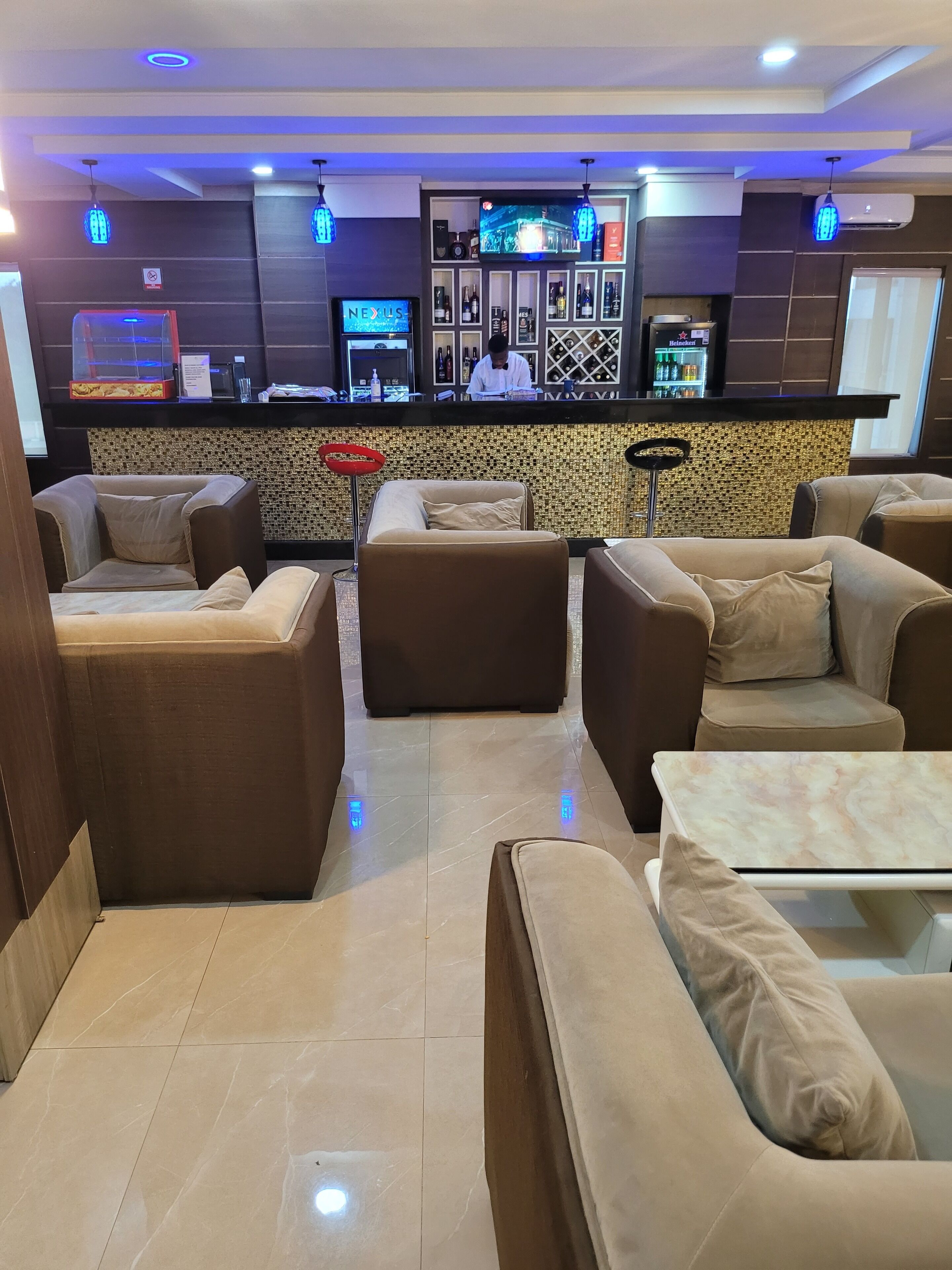 A modern bar area with seating, a television, and a Heineken refrigerator.