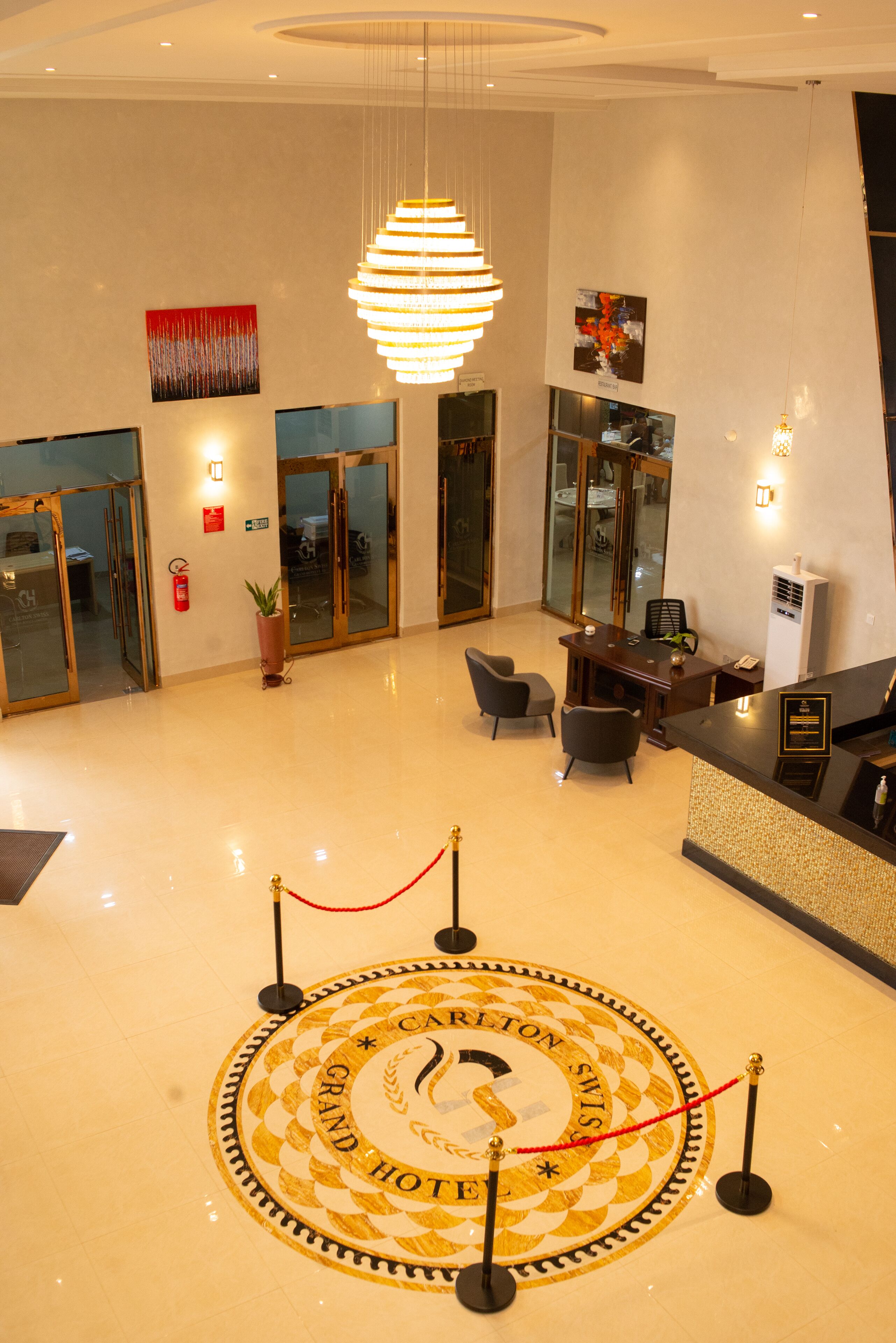 A hotel lobby with a reception desk, seating area, and a circular emblem on the floor.