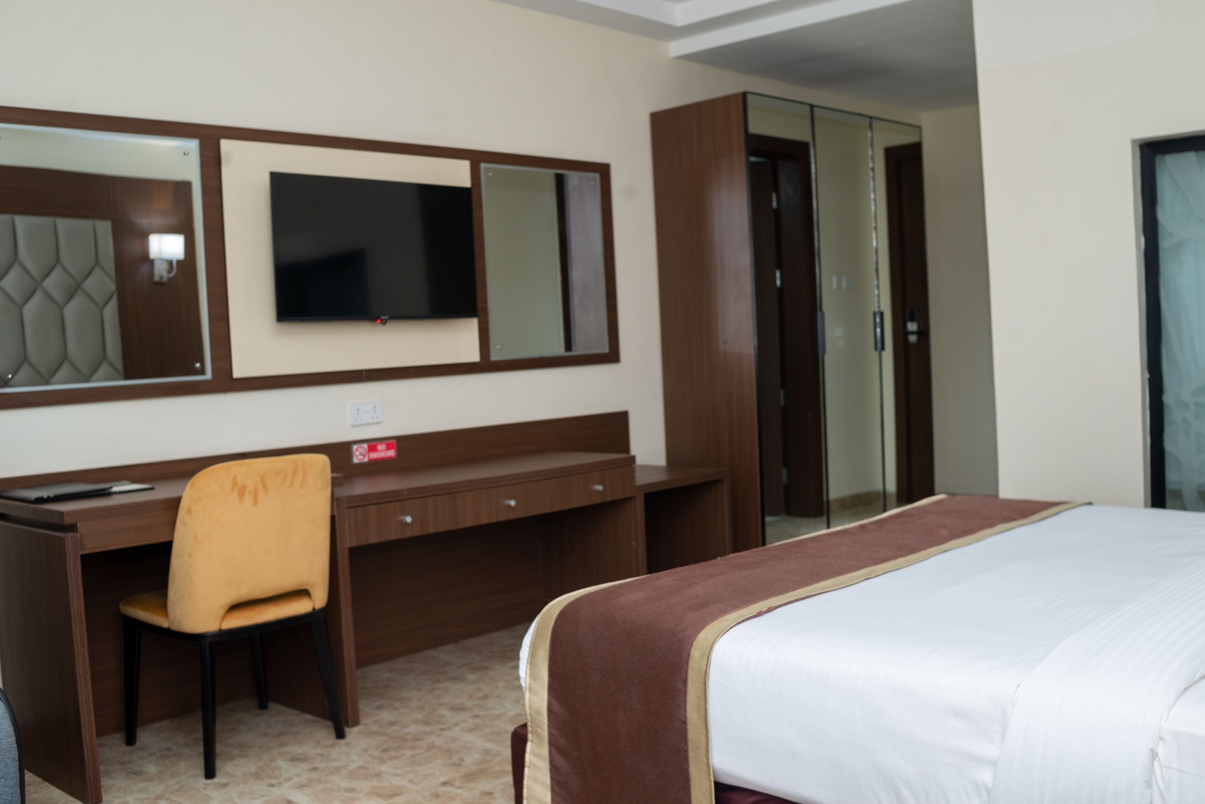 Una habitación de hotel con una cama, un escritorio con silla, un televisor y un armario.