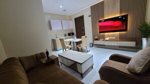 Een moderne woonkamer met een bank, een salontafel en een televisie die aan de muur is bevestigd.