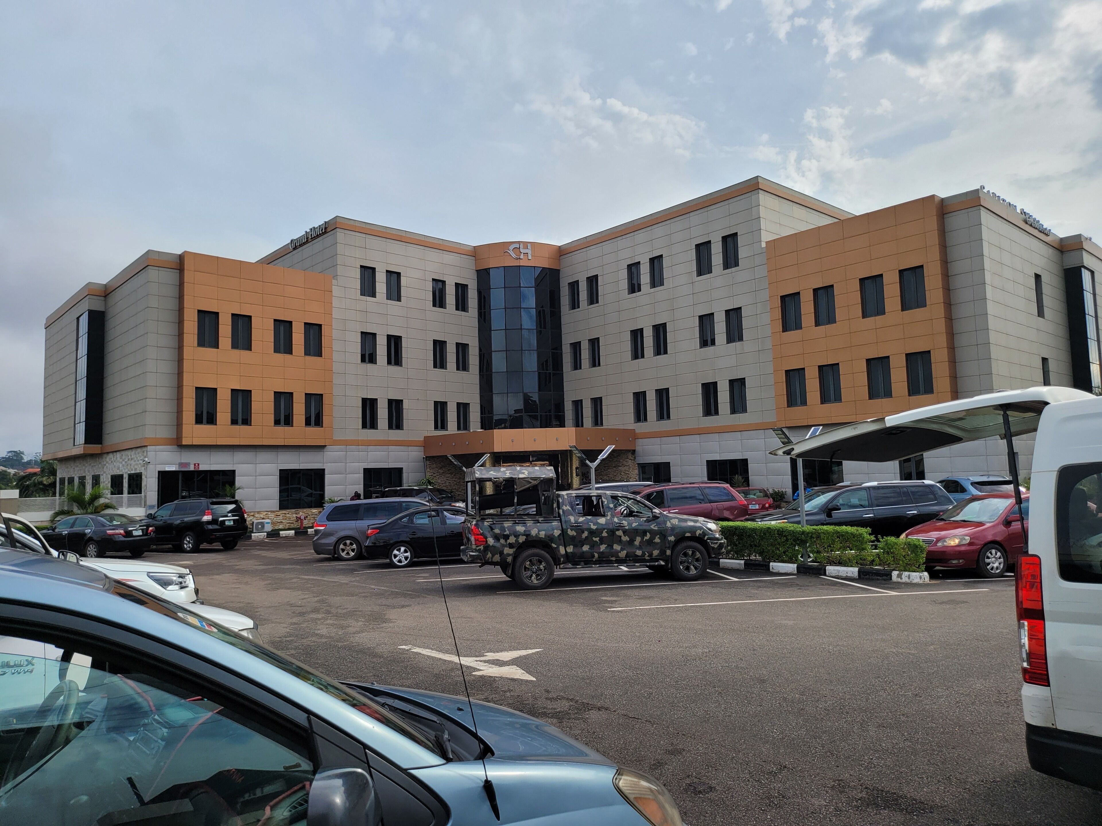 A multi-story hotel with a modern design, featuring a central entrance and multiple parking spaces.