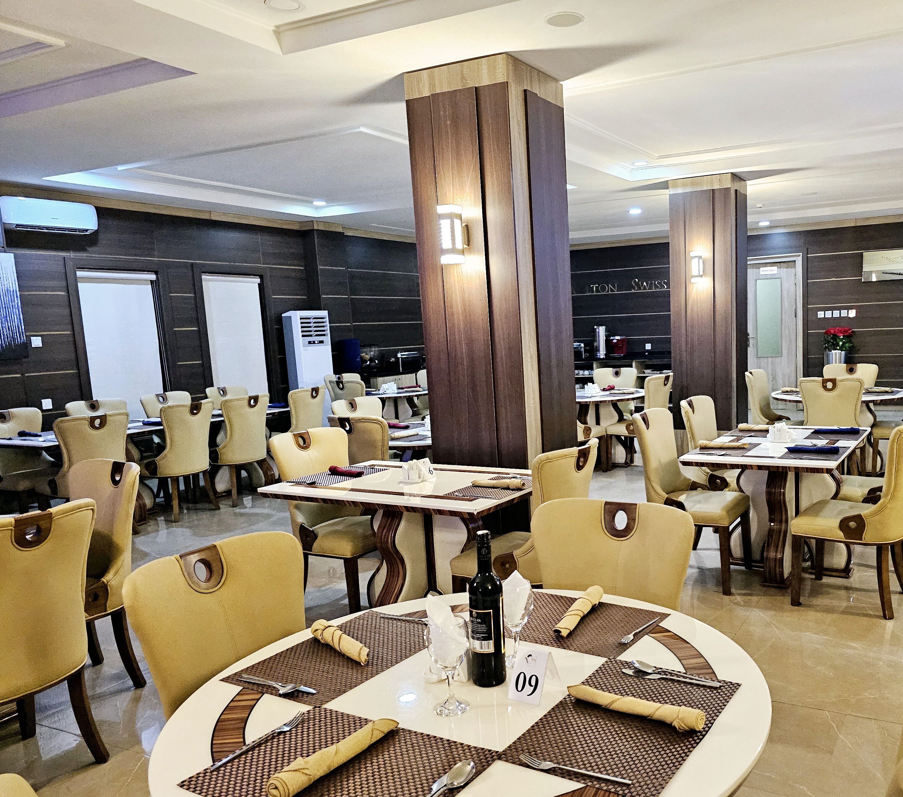 Un restaurante con varias mesas y sillas, una botella de vino y un menú sobre la mesa.