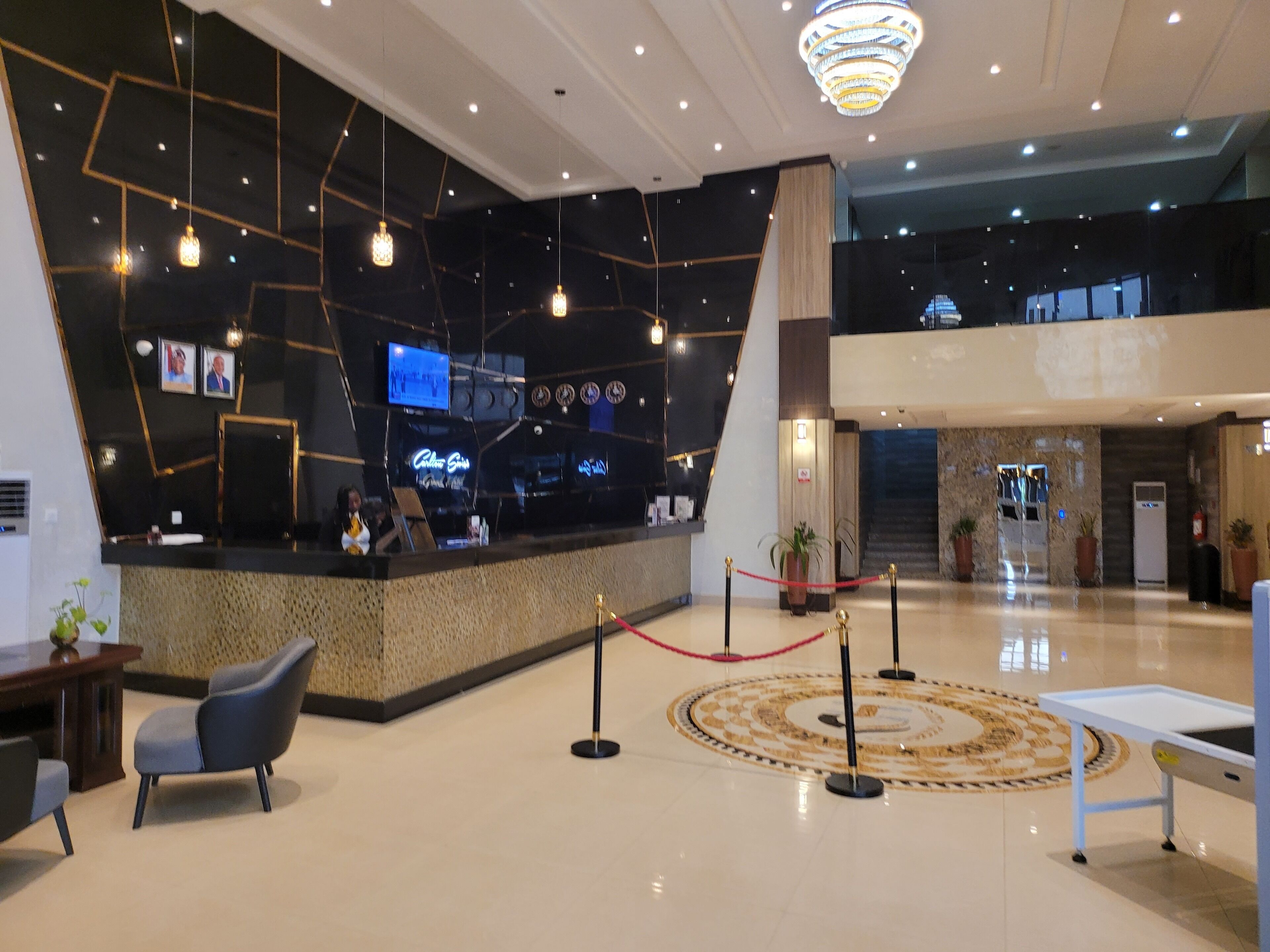 A modern lobby with a reception desk, seating area, and a decorative floor pattern.