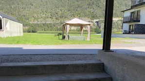 A concrete staircase leading to a covered outdoor area with a view of a mountain and a building in the background. - Apartment Business (Imsterberg)