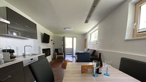 A modern kitchen with a dining area, a fireplace, and a large window. - Apartment Business (Imsterberg)