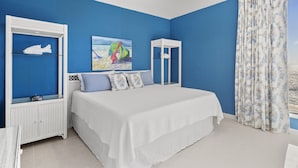 Een slaapkamer met een groot bed, een plafondventilator, een raam met gordijnen en een schilderij aan de muur.