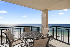 A balcony with a round table and chairs, overlooking a beach and the ocean. - Gulf front!! 11th floor Right on the beach! With free beach service (Navarre)