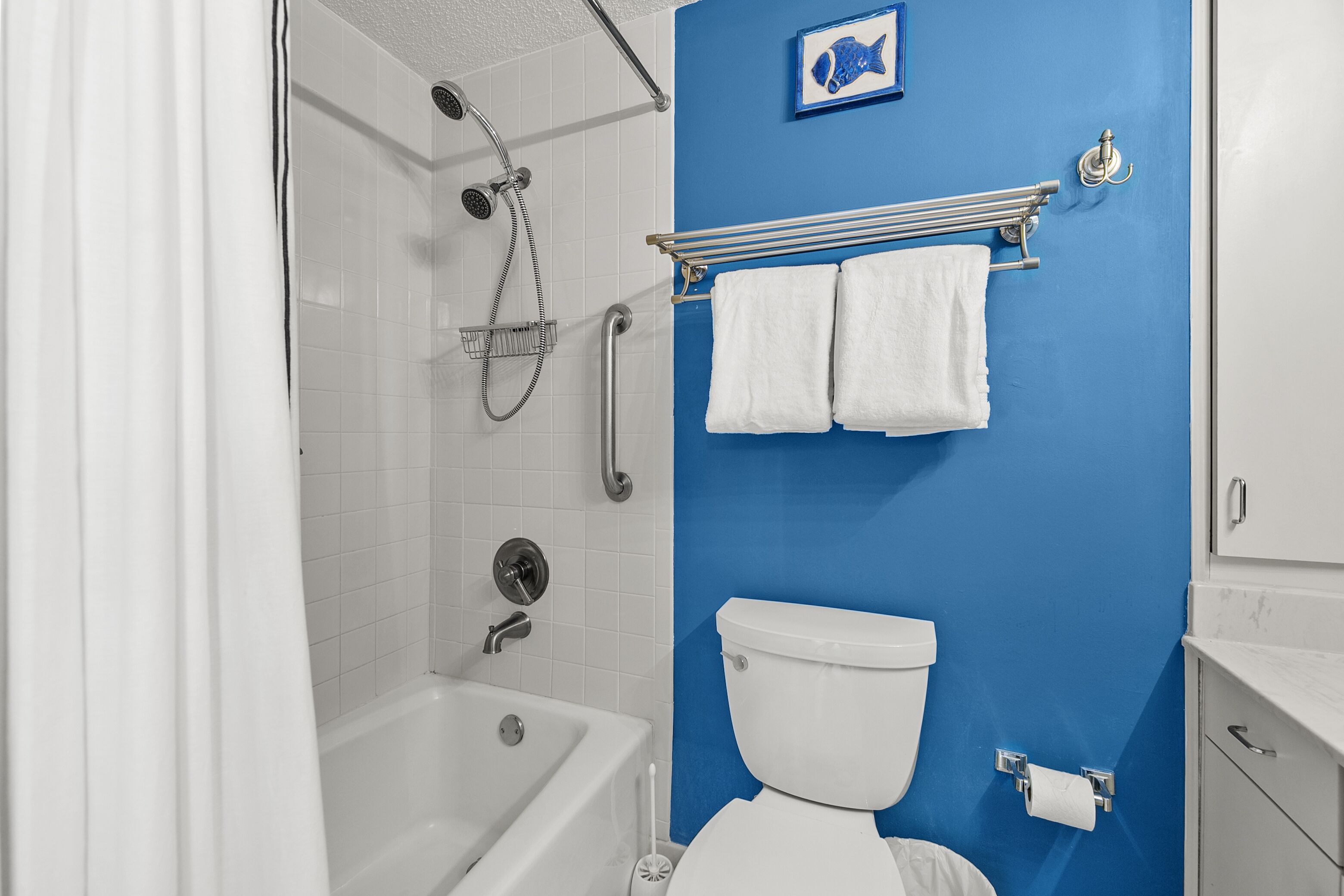 Ein Badezimmer mit einer Badewanne, einer Dusche, einer Toilette und einem Handtuchhalter.