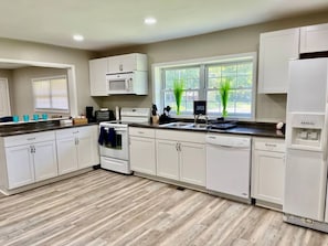 A modern kitchen with white cabinetry, a built-in microwave, a stove, a sink, and a dishwasher.