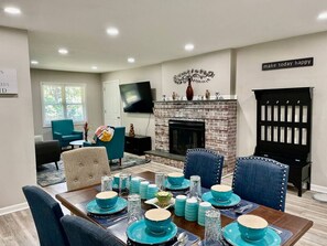 Un comedor con chimenea de ladrillo, vajilla color turquesa y decoración moderna.