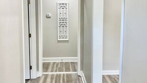 A hallway with a wooden floor, white walls, and a decorative panel on the door. - Modern High Point Getaway | 3BR, HPU & RV Space (High Point)