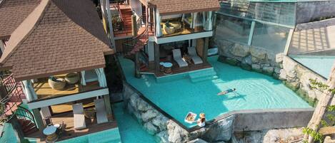 A resort with multiple swimming pools, lounge areas, and a central pool with a rocky edge.