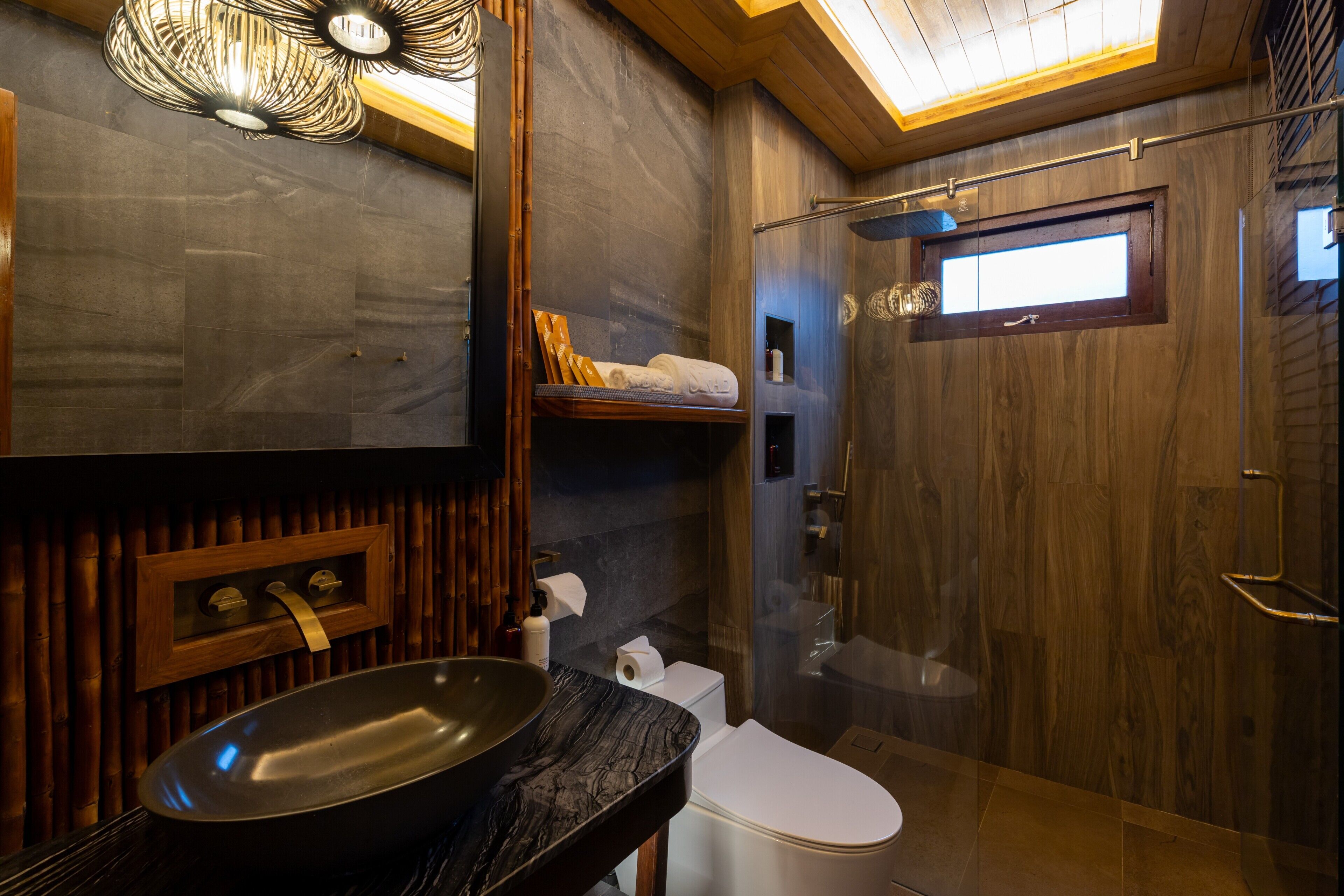 A modern bathroom with a large mirror, a vessel sink, a toilet, and a shower enclosure.
