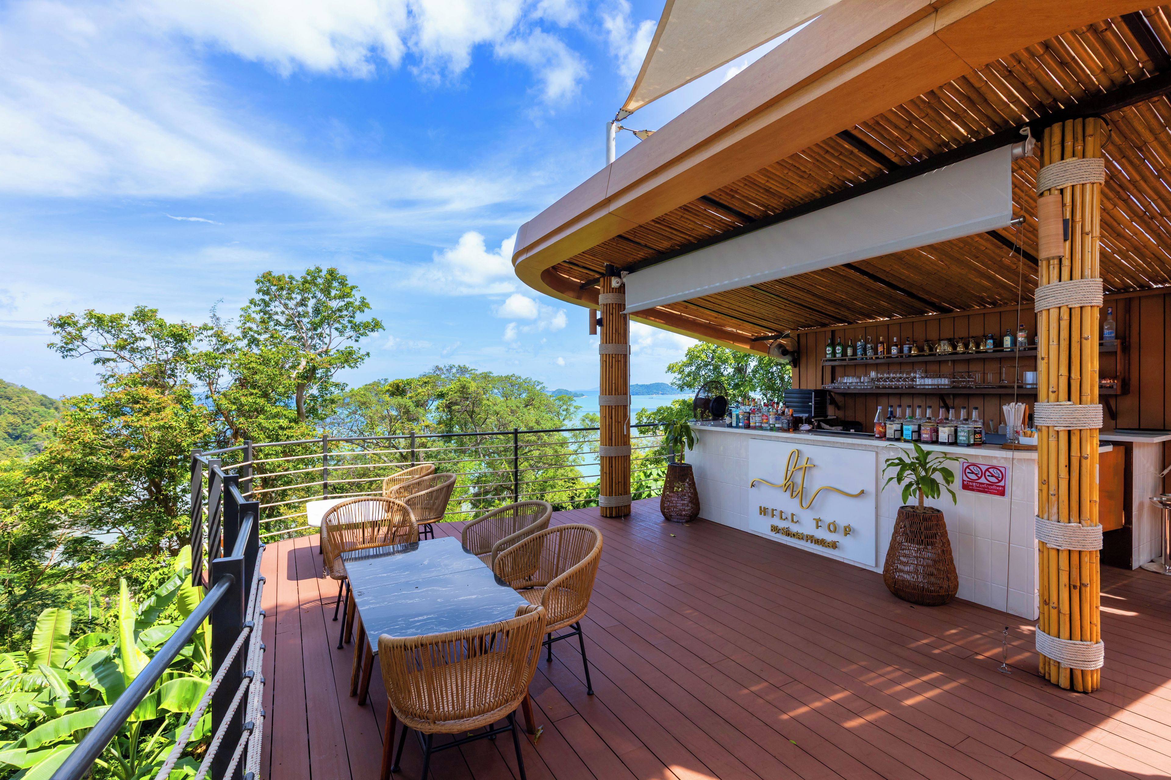 A wooden deck with wicker chairs and a bar area with a view of the mountains.