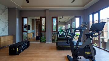 A gym with exercise equipment, a wooden floor, and large windows.