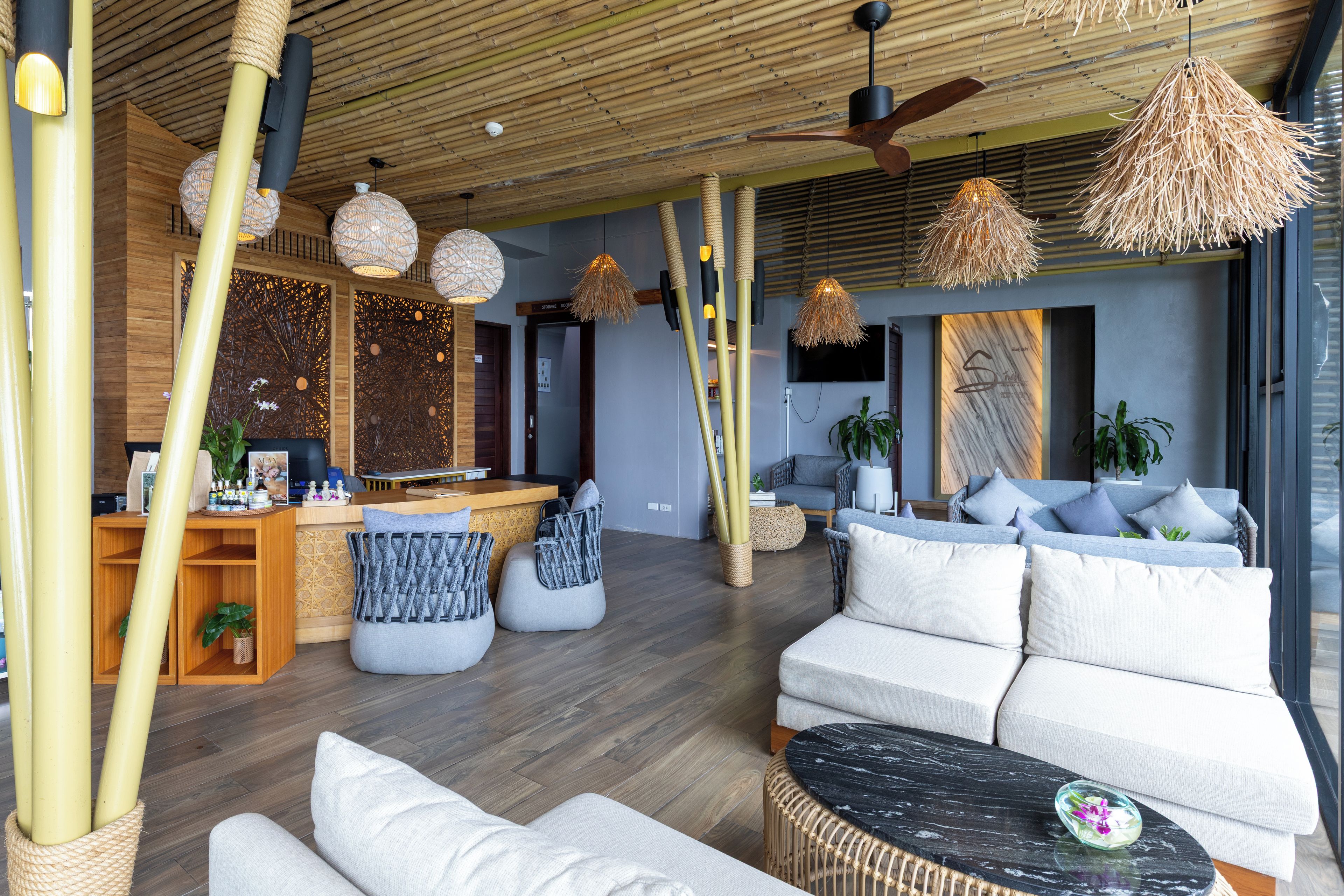 Un intérieur moderne comprenant un comptoir d’accueil, un espace détente et un ventilateur de plafond.