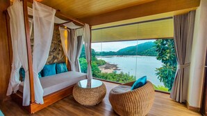Une chambre avec un lit, une vue sur un lac et des meubles en osier.