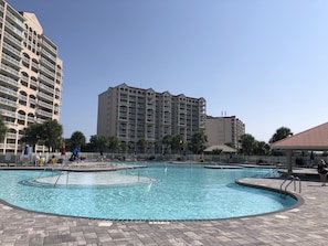 Un espace piscine comprenant plusieurs bassins, entouré d’une clôture et situé à côté d’immeubles résidentiels de grande hauteur.