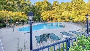 A swimming pool with lounge chairs and a lamp post.
