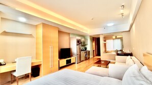 A modern hotel room with a large bed, a desk, a TV, a kitchenette, and a bathroom. - Tianjin Crown International Apartments (Tianjin)