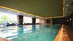 An indoor swimming pool with clear water, lane dividers, and lounge chairs along the side. - Tianjin Crown International Apartments (Tianjin)