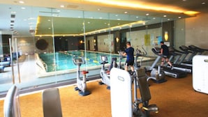 A gym with a swimming pool, treadmills, and exercise equipment. - Tianjin Crown International Apartments (Tianjin)