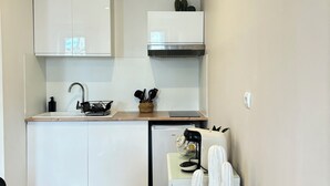 Una cocina compacta con armarios blancos, horno empotrado, cafetera y una decoración con cactus.