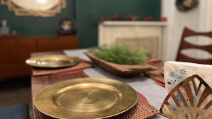 Un tavolo da pranzo con una piastra in ottone, un sottopiatti intrecciato e una sedia decorativa.