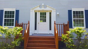 A two-story house with a front door, a wooden staircase, and a small porch. - Bar Harbor Serenity close to Hadley Point Beach (Bar Harbor)