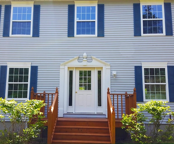 A two-story house with a front door, a wooden staircase, and a small porch.