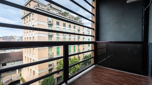 Een balkon met uitzicht op omliggende gebouwen, een metalen hekwerk en een deur.