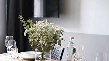 Una mesa de comedor dispuesta con platos, vasos y un florero con flores.