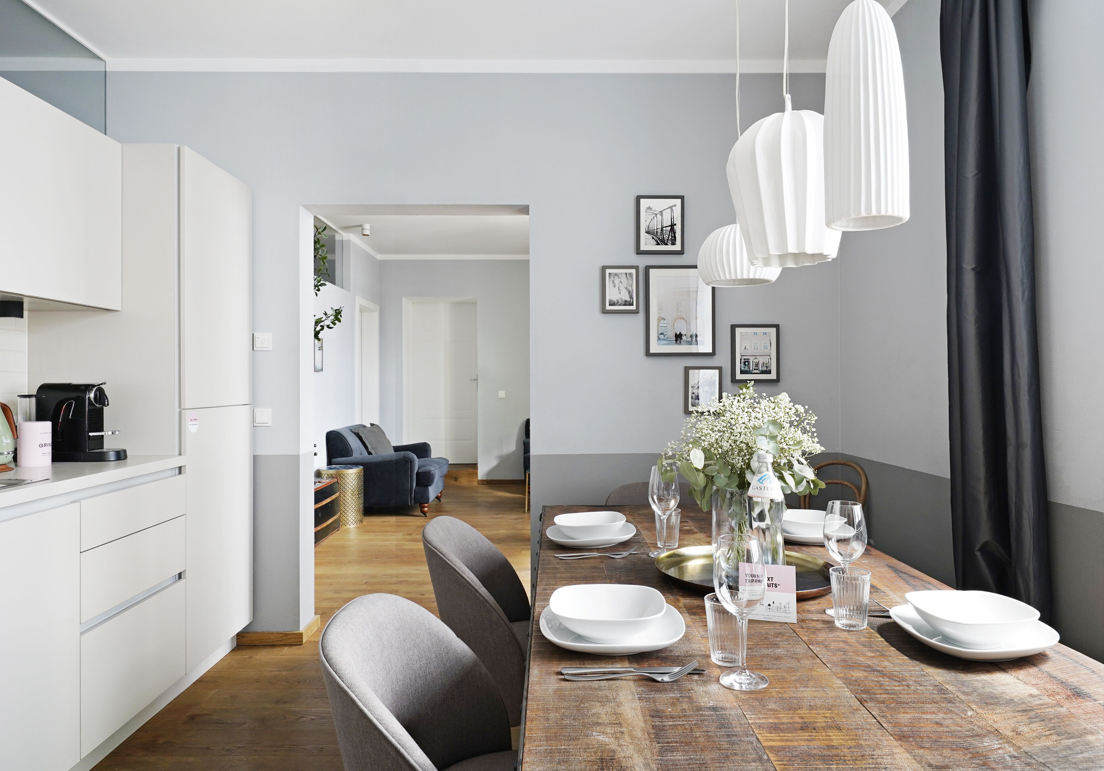 Un comedor moderno con una mesa de madera dispuesta para cuatro, platos blancos y vasos transparentes.