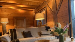 A cozy cabin interior with a wooden sofa, a table with a bowl, and a vase with flowers.
