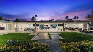 A modern house with a spacious patio, a dining area, and a well-maintained lawn. - 7BR Luxury Retreat - Cedar Sauna, Gym, Heated Pool, Spa, Basketball & Foosball (Scottsdale)