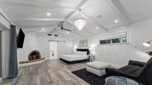 A spacious living room with a fireplace, a ceiling fan, and a chandelier. - 7BR Luxury Retreat - Cedar Sauna, Gym, Heated Pool, Spa, Basketball & Foosball (Scottsdale)
