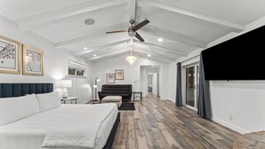 A spacious bedroom with a large bed, a ceiling fan, and a chandelier. - 7BR Luxury Retreat - Cedar Sauna, Gym, Heated Pool, Spa, Basketball & Foosball (Scottsdale)
