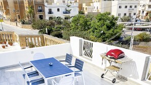 Terraza en la azotea con jacuzzi, mesa, sillas y carrito para barbacoa.