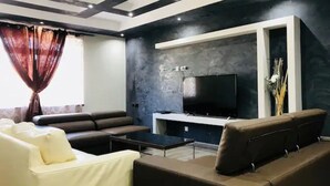 Una sala de estar moderna con un televisor de pantalla plana, sofás de cuero y una mesa de centro.