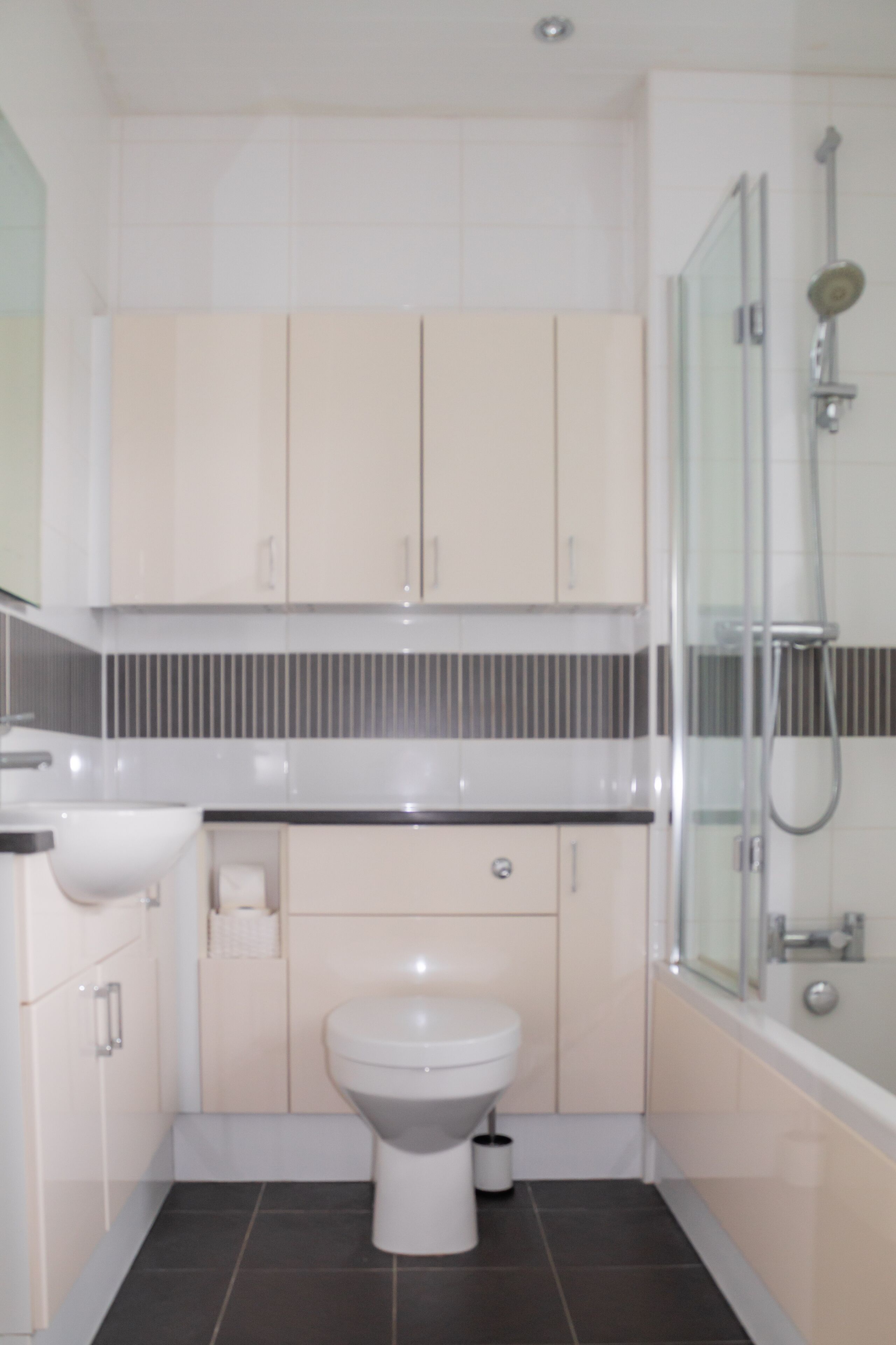 A modern bathroom with a toilet, sink, and shower.