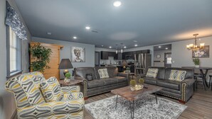 Ein modernes Wohnzimmer mit grauem Sofa, einem gemusterten Sessel und einem Couchtisch.