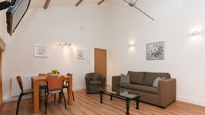 Un salon comprenant une table à manger en bois, un canapé marron, une table basse en verre et un fauteuil gris.