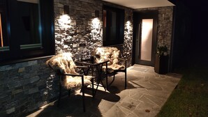 Un patio al aire libre con paredes de piedra, dos sillas y una mesa.