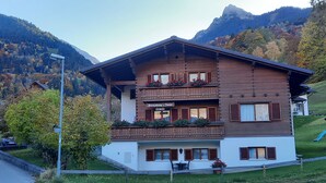 Una cabaña de madera de varios pisos con balcones, un letrero que indica un restaurante y un telón de fondo montañoso.