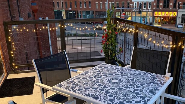 Une terrasse sur le toit, avec une table et des chaises, des guirlandes lumineuses et une vue sur le paysage urbain.