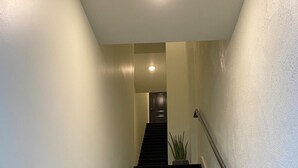 Un escalier muni d’une rampe, menant à une porte située en haut.